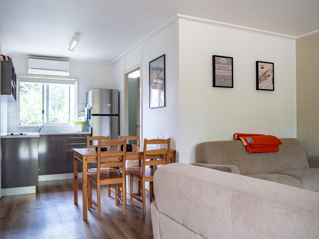 An open-plan living room with two sofas, a timber dining table and the kitchen behind