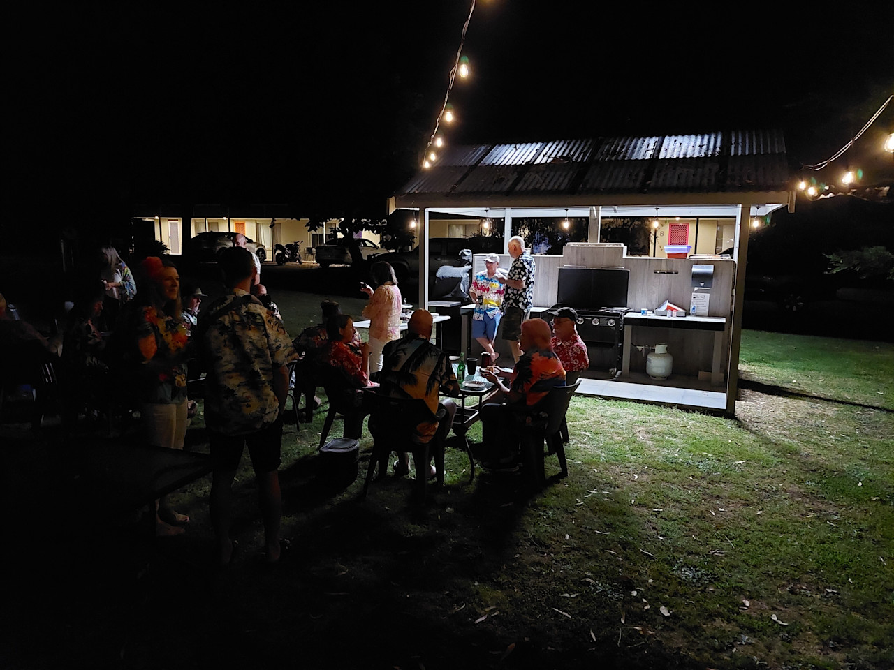 Guests gathered at the barbecue area in the evening under string lights