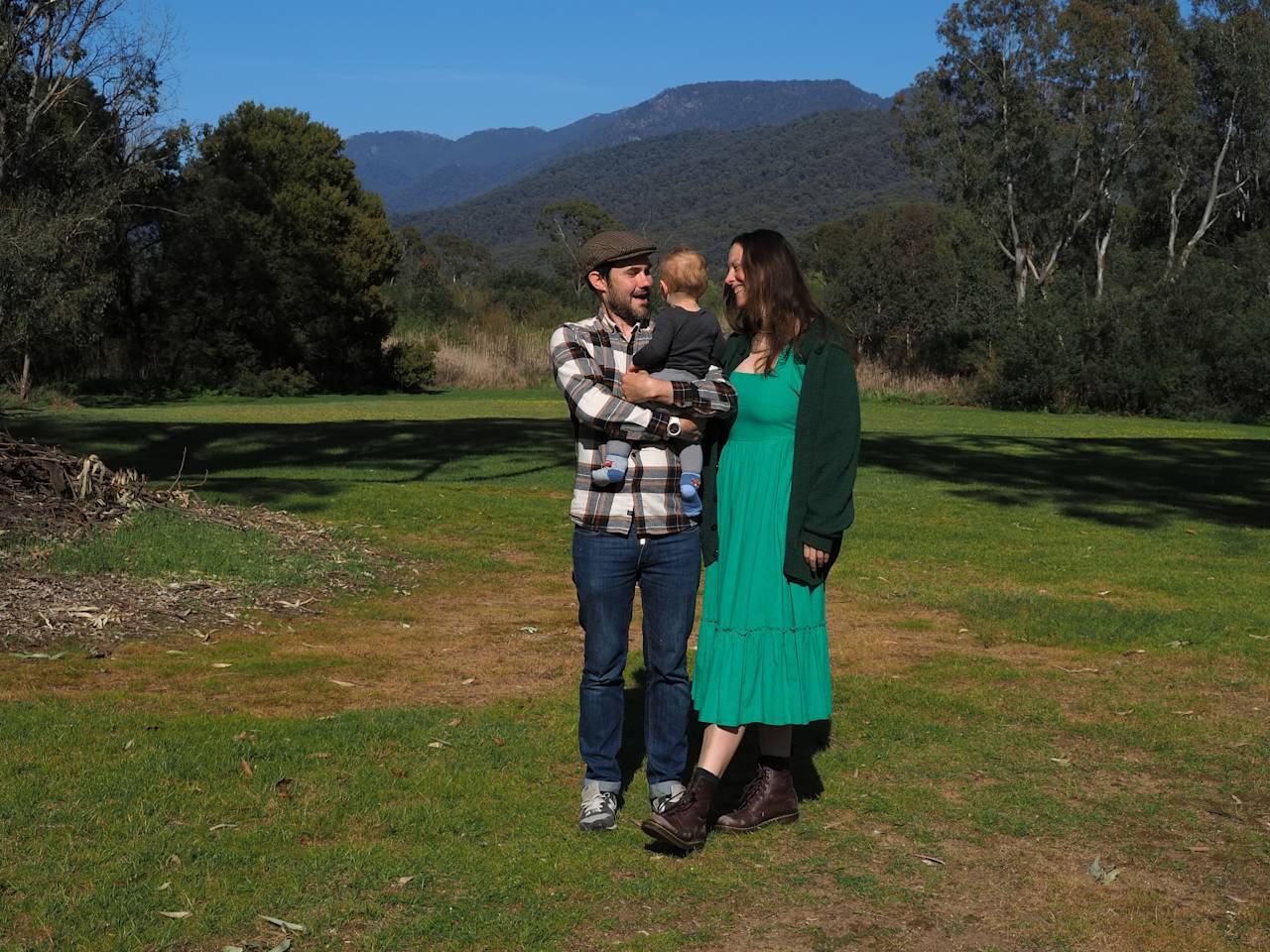 The owners holding their young child on the back lawn, with the ranges behind them